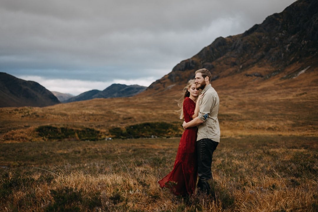 Cuddling couple in Buachaille Etive Mòr in Glen Etive in the Scottish Highlands who are on an adventure session