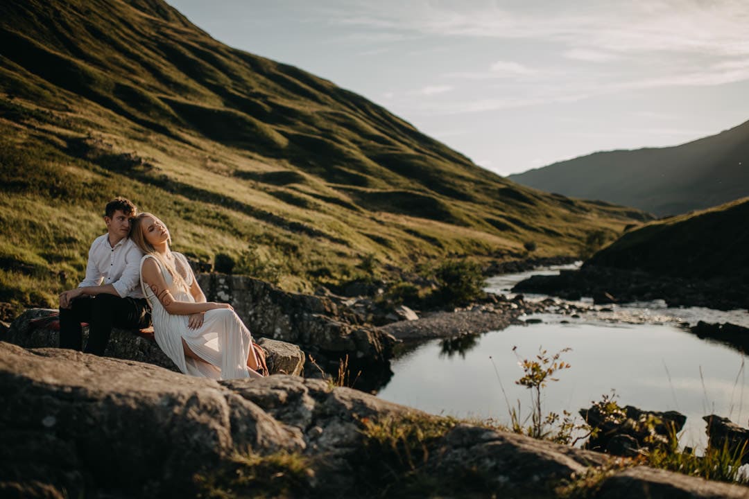 Eloping couple sitting on rock in Glen Etive