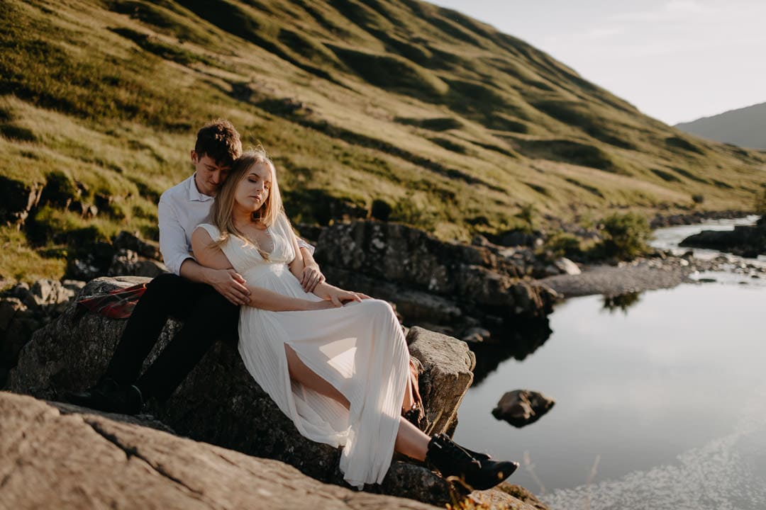 Eloping couple sitting on rock in Glen Etive