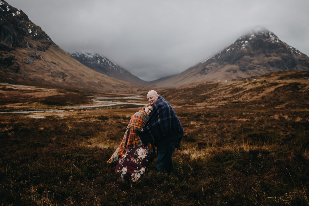 Buachaille Etive Mhor in Glencoe on romantic couples adventure session wearing a tartan blanket