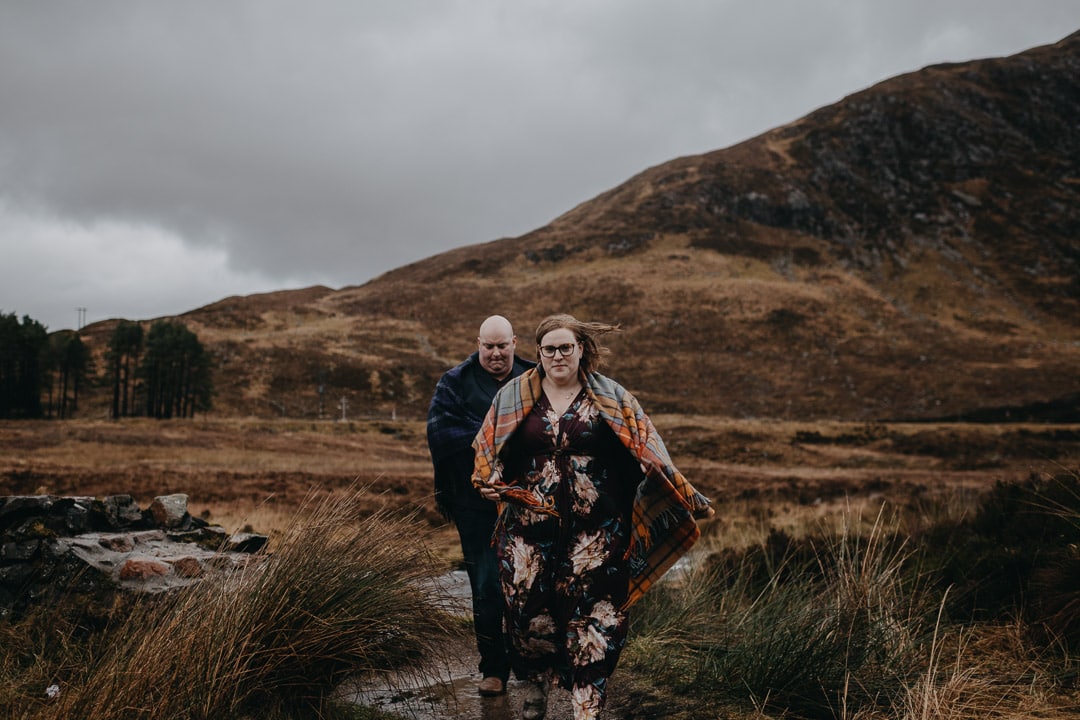 Exploring Buachaille Etive Mhor in Glencoe on couples adventure session wearing a Tartan blanket