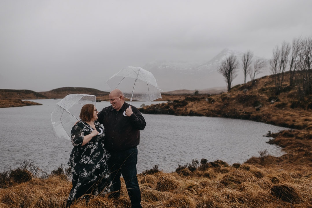 Holding umbrellas on a winter rainy couples session in Glencoe, Scotland