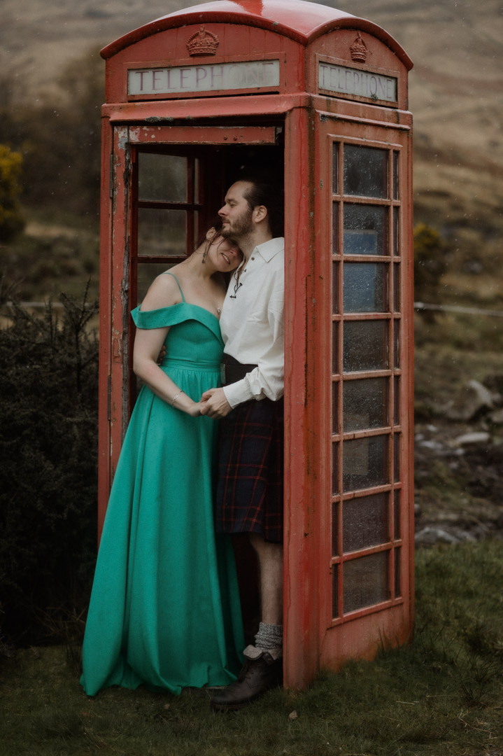 Wet elopement couple on Isle of Mull hiding in the telephone box for shelter