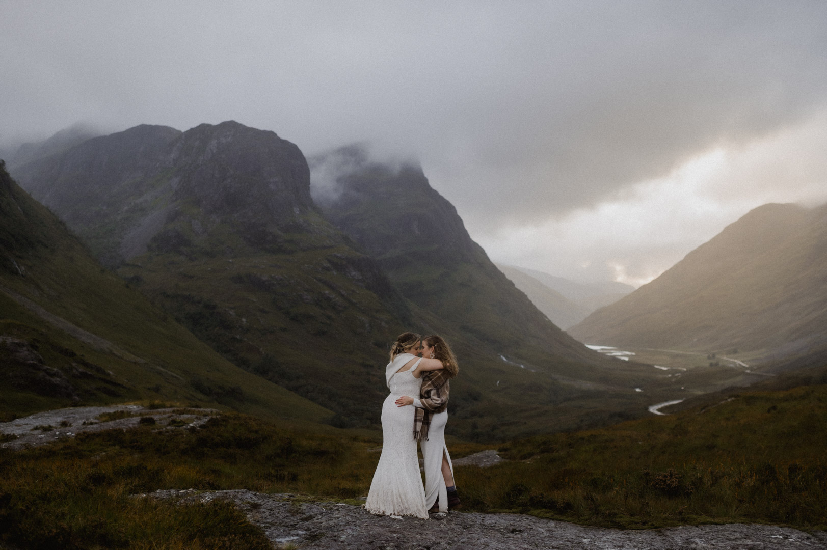 Glencoe elopement with stormy sunset - two brides cuddling