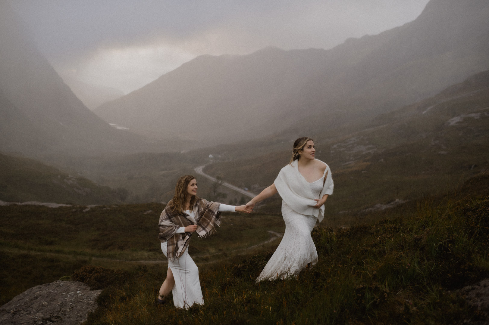 Climbing hill in Glencoe during stormy sunset - same-sex couple