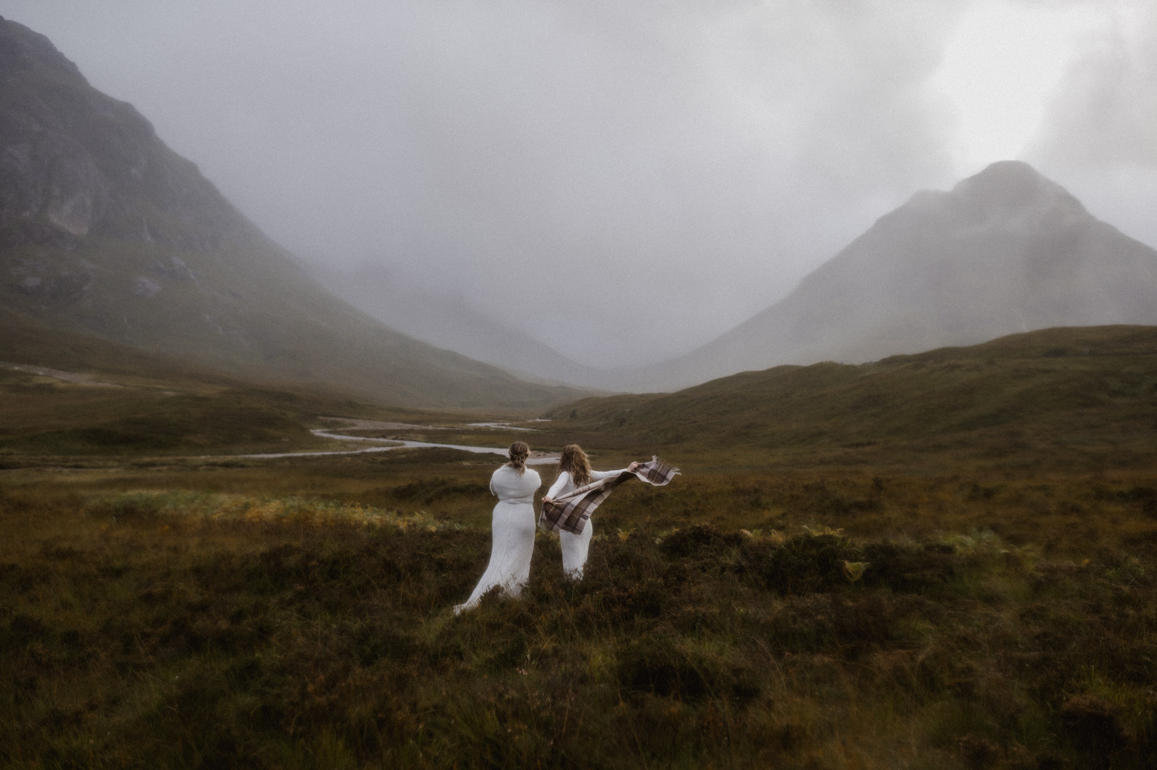 Lesbian couple exploring Glencoe in stormy Autumn