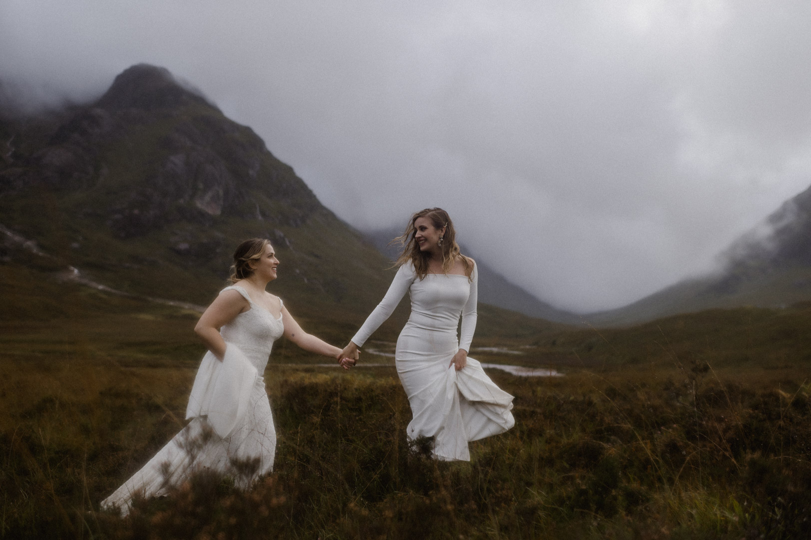 Lesbian couple exploring Glencoe in stormy Autumn