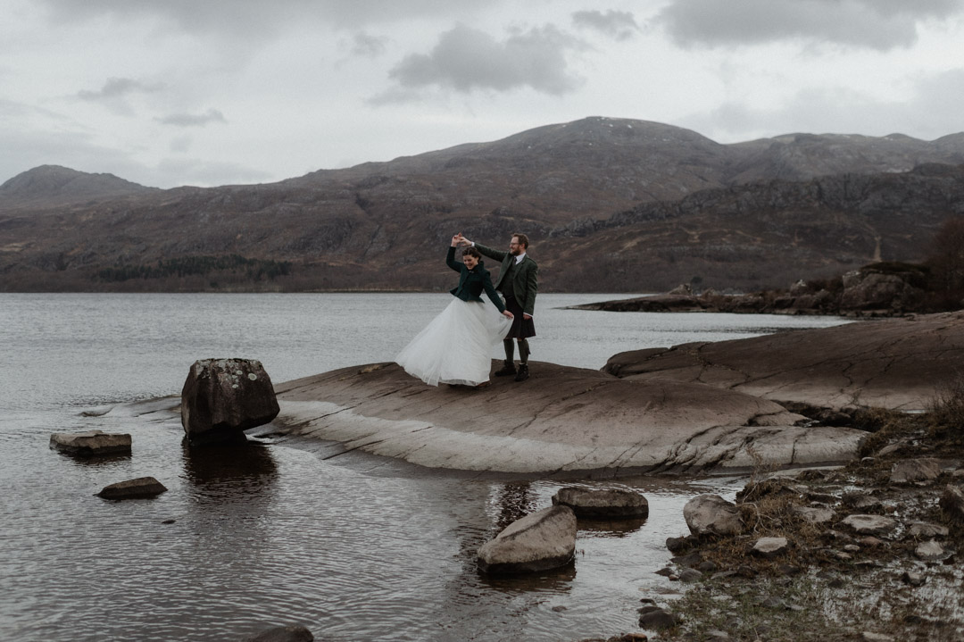 Winter elopement couple dancing by loch in Scottish Highlands