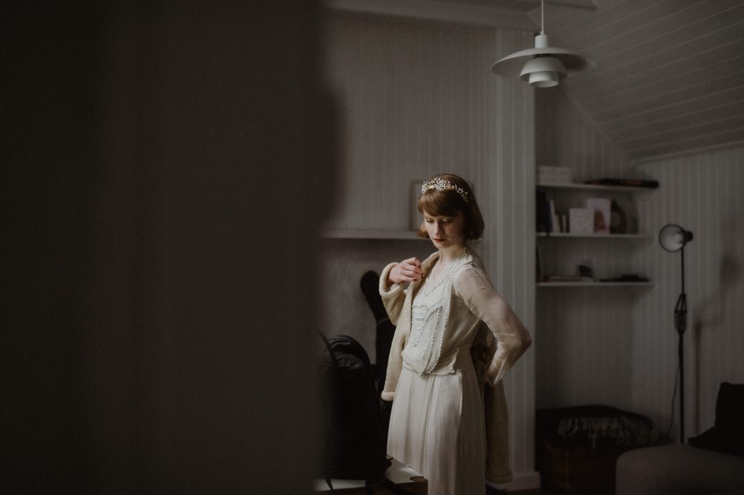 Quiet soulful elopement on Isle of Skye with vintage styling - bride puts on coat
