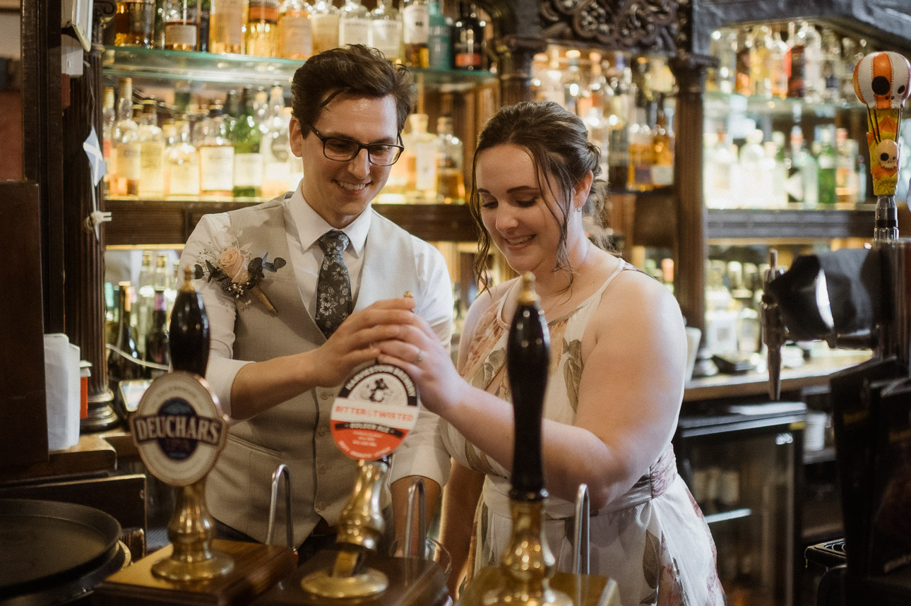 Couple pulling a pint in a scottish pub on their elopement day