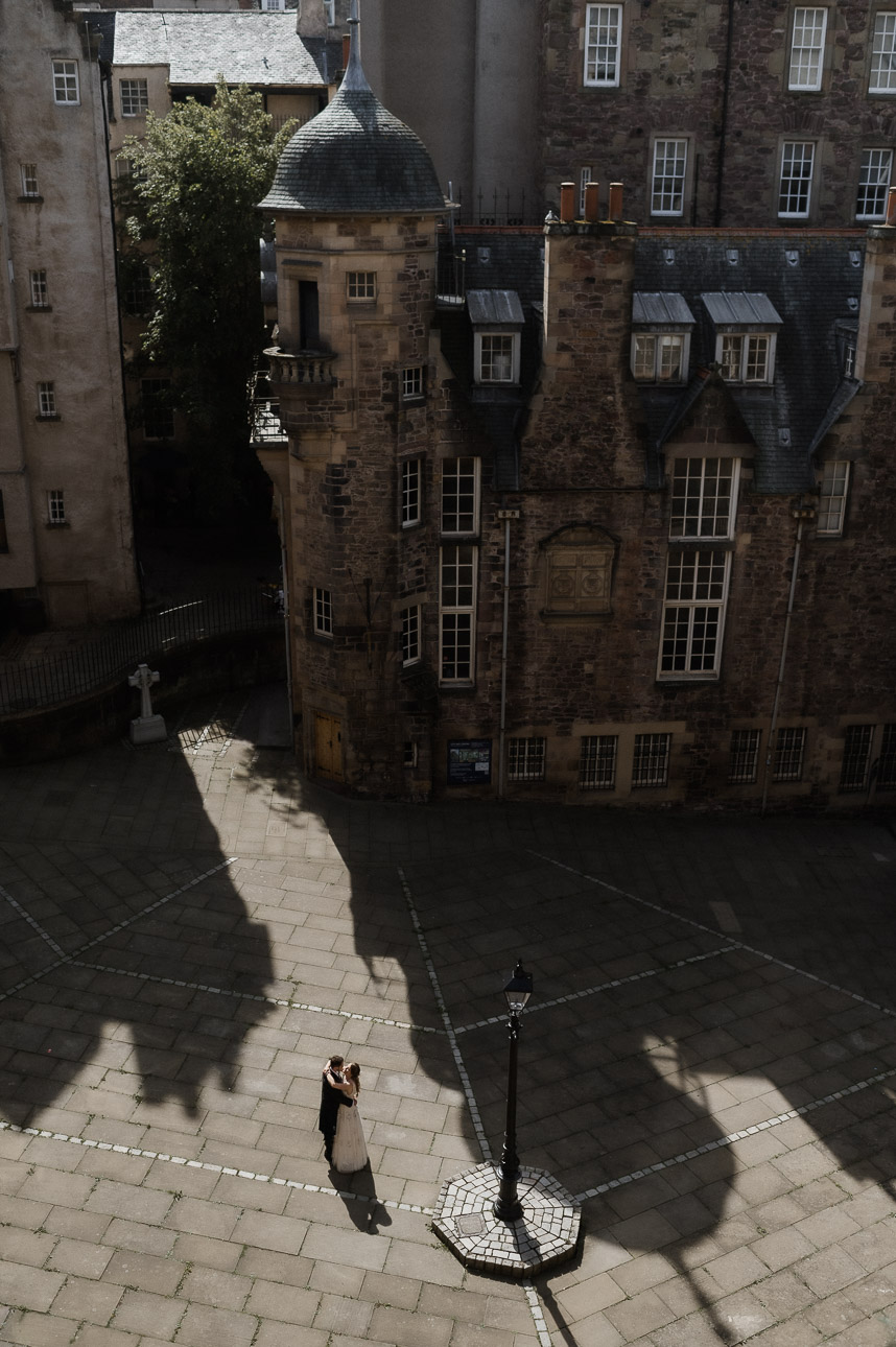 Couple standing in a close on the royal mile from below