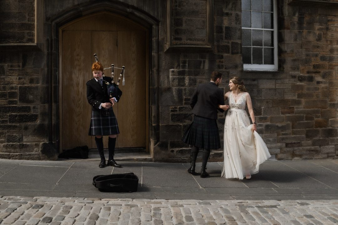 Couple dancing with bagpiper during elopement