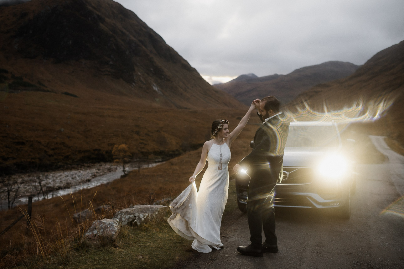 Glencoe elopement day transportation - couple dancing in front of volvo 4x4 headlights at dusk